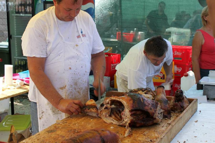 De slager druk bezig met gebraden varken 